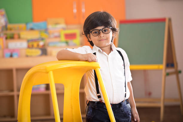 Little preschool boy standing at classroom